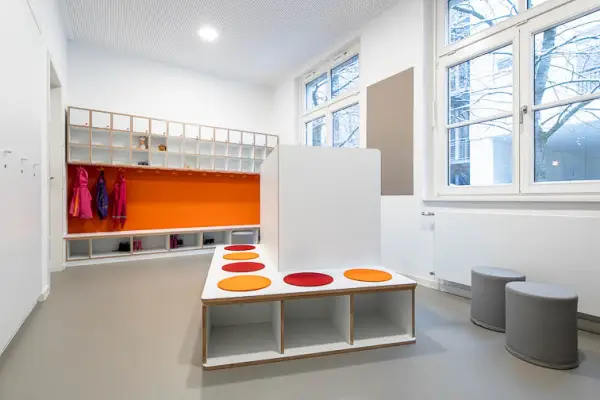 Innenraumperspektive der Garderobe mit Einbaumöbeln und farblichen Akzenten in Orange- und Rottönen